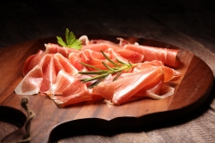 Italian prosciutto crudo or jamon with rosemary. Raw ham on wood